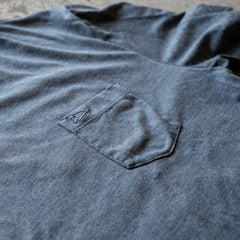 A close-up of the Short Sleeve Pocket Tee - Tri-BlendX in blue showcases its small stitched pocket and the arrow design above it, highlighting the tee's classic simplicity and versatile style.