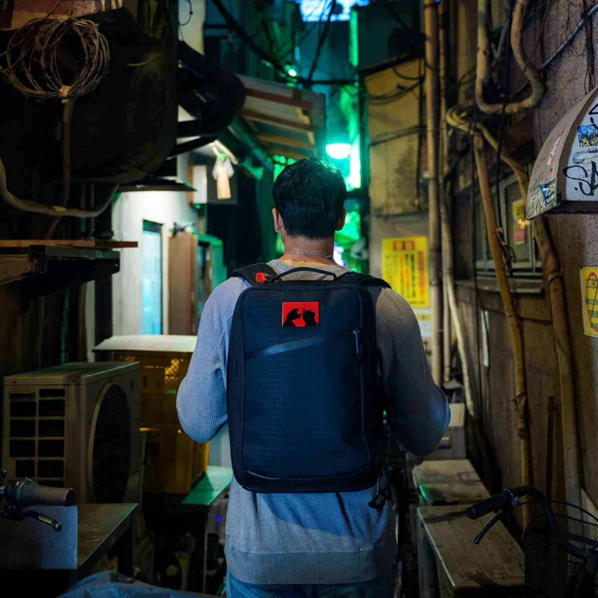 Man with GORUCK rucksack walking through urban alley at night, rugged outdoor gear