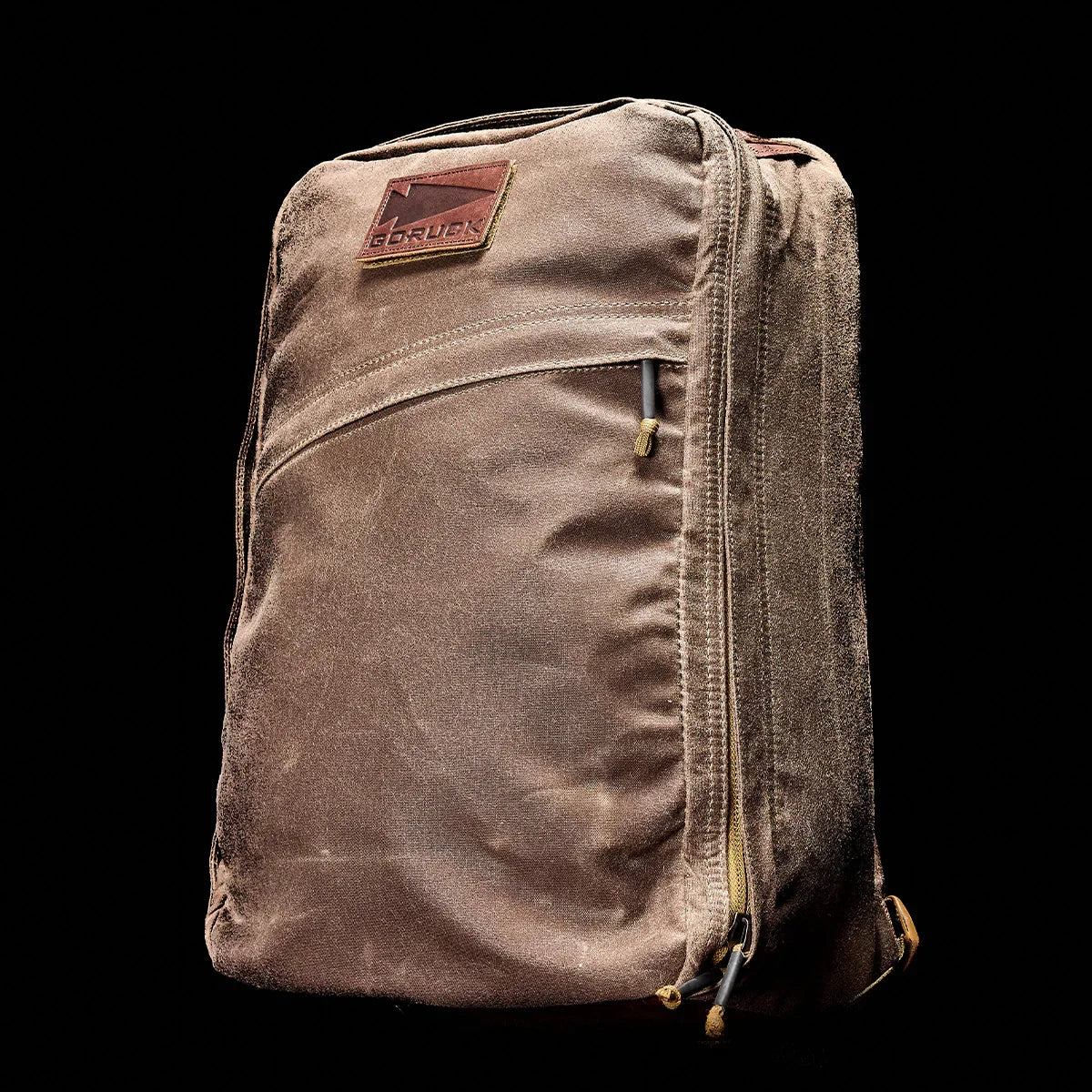 GORUCK rugged brown rucksack backpack with front zipper pocket against black background