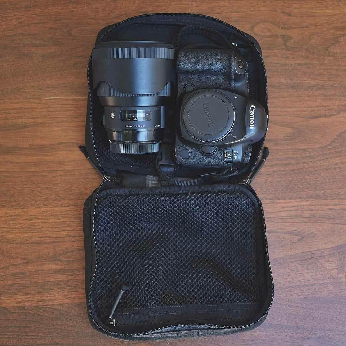 GORUCK black camera case with Canon EOS DSLR and Sigma lens on wooden surface