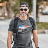 Man wearing GORUCK Flag Spearhead charcoal tee, backpack, and sunglasses outdoors