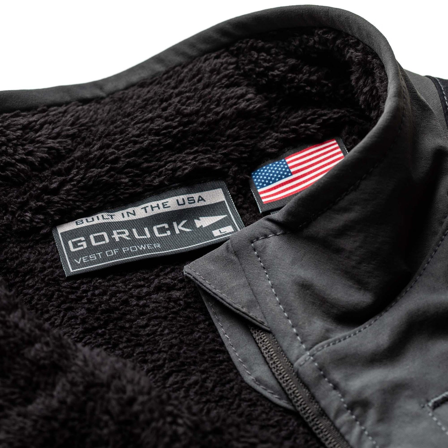 GORUCK charcoal fleece vest close-up, USA-made inner label and American flag tag