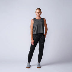 Woman in GORUCK athletic gear, gray tank top, black joggers, and sneakers, studio photo
