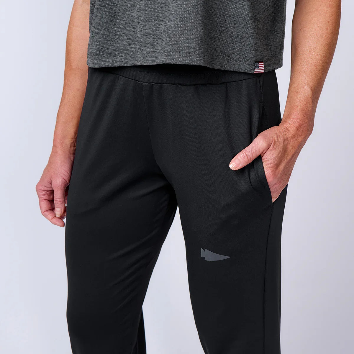 GORUCK black athletic pants with hand in pocket, close-up studio shot