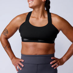 Athletic woman wearing GORUCK black sports bra and grey workout leggings, studio setting