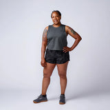 Woman in GORUCK athletic gear, gray tank top and black shorts, studio background
