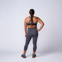 Woman in GORUCK athletic gear, gray leggings and sports bra, standing in studio