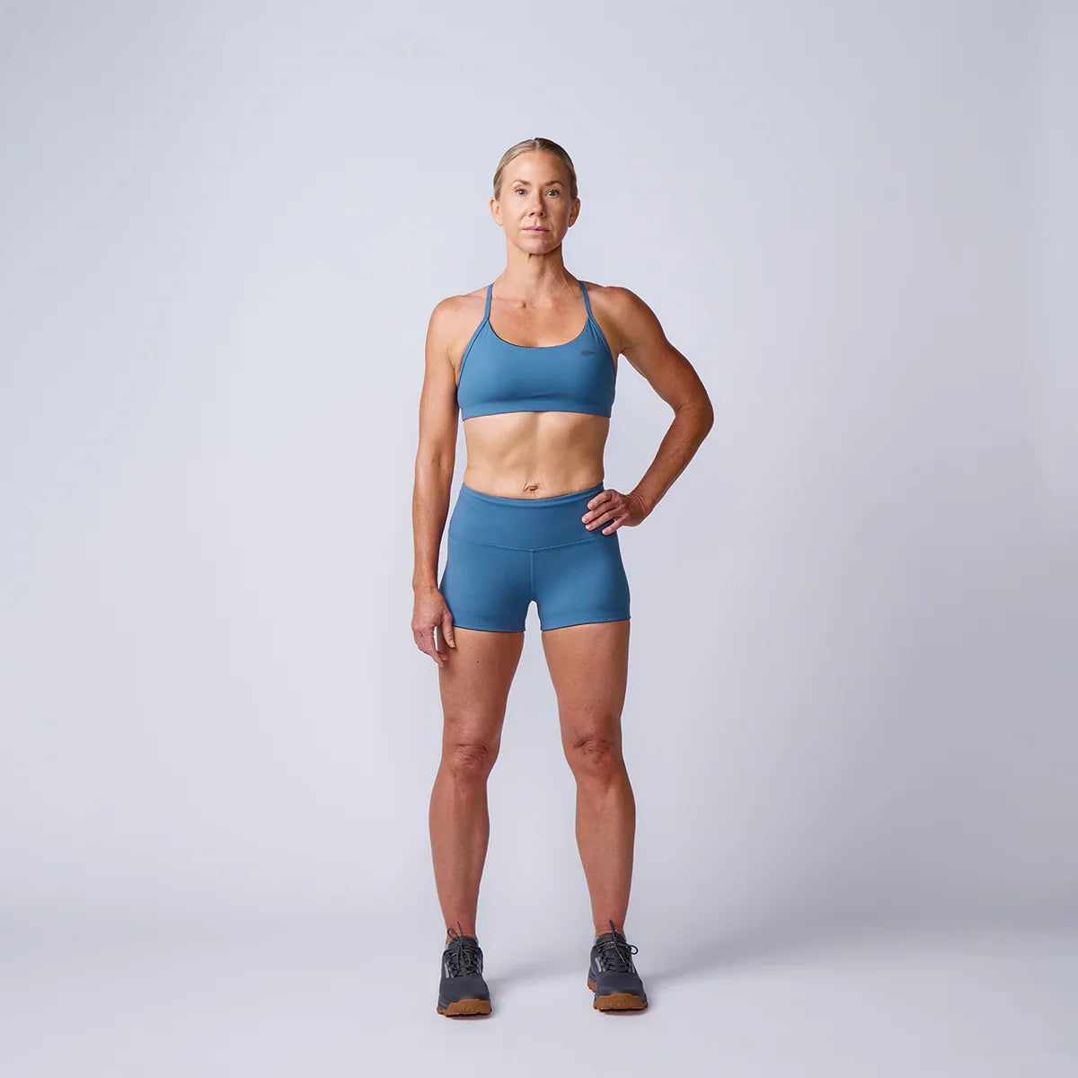 Athletic woman in blue sports bra and shorts modeling GORUCK rucking gear in studio