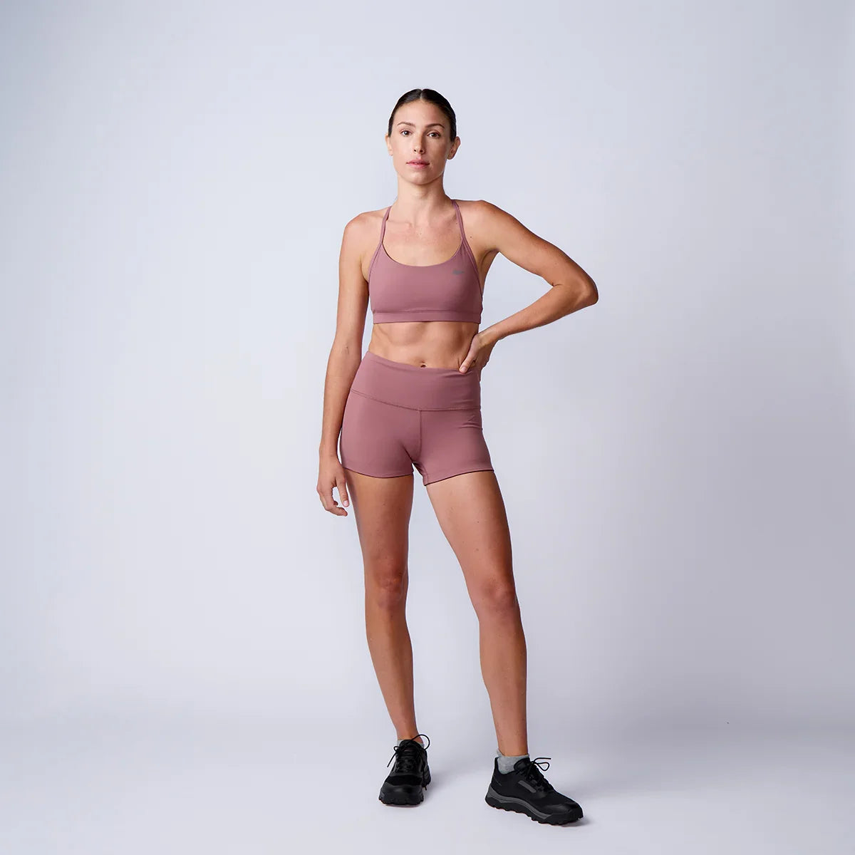 Woman in mauve sports bra and shorts modeling GORUCK rucking workout gear in studio