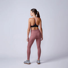 Woman in athletic wear facing away, wearing mauve leggings, sports bra, and GORUCK shoes