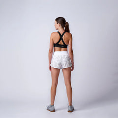Woman wearing GORUCK sports bra and camo shorts, rucking gear studio shoot, rear view