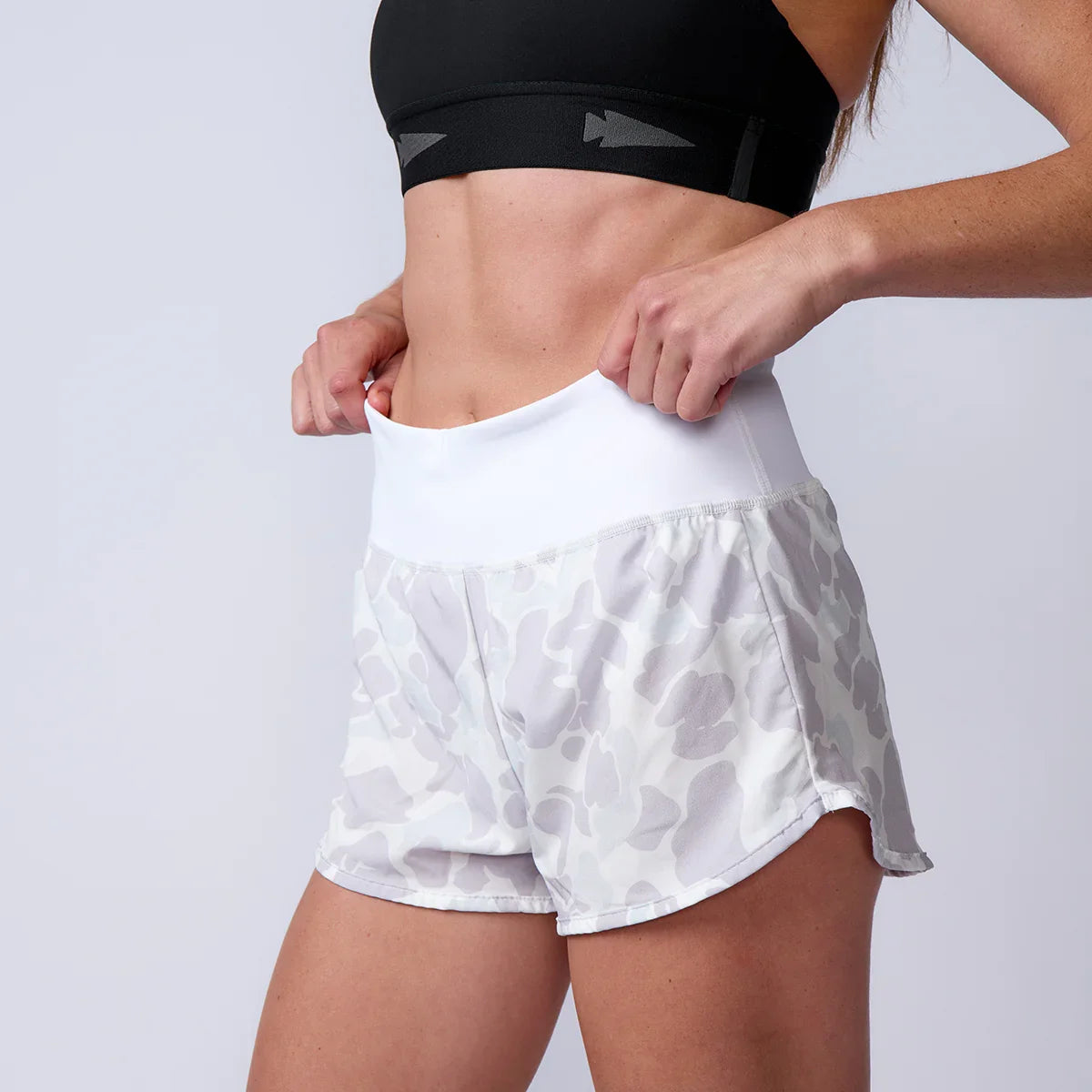 GORUCK athletic woman in camo rucking shorts and black sports bra adjusting waistband