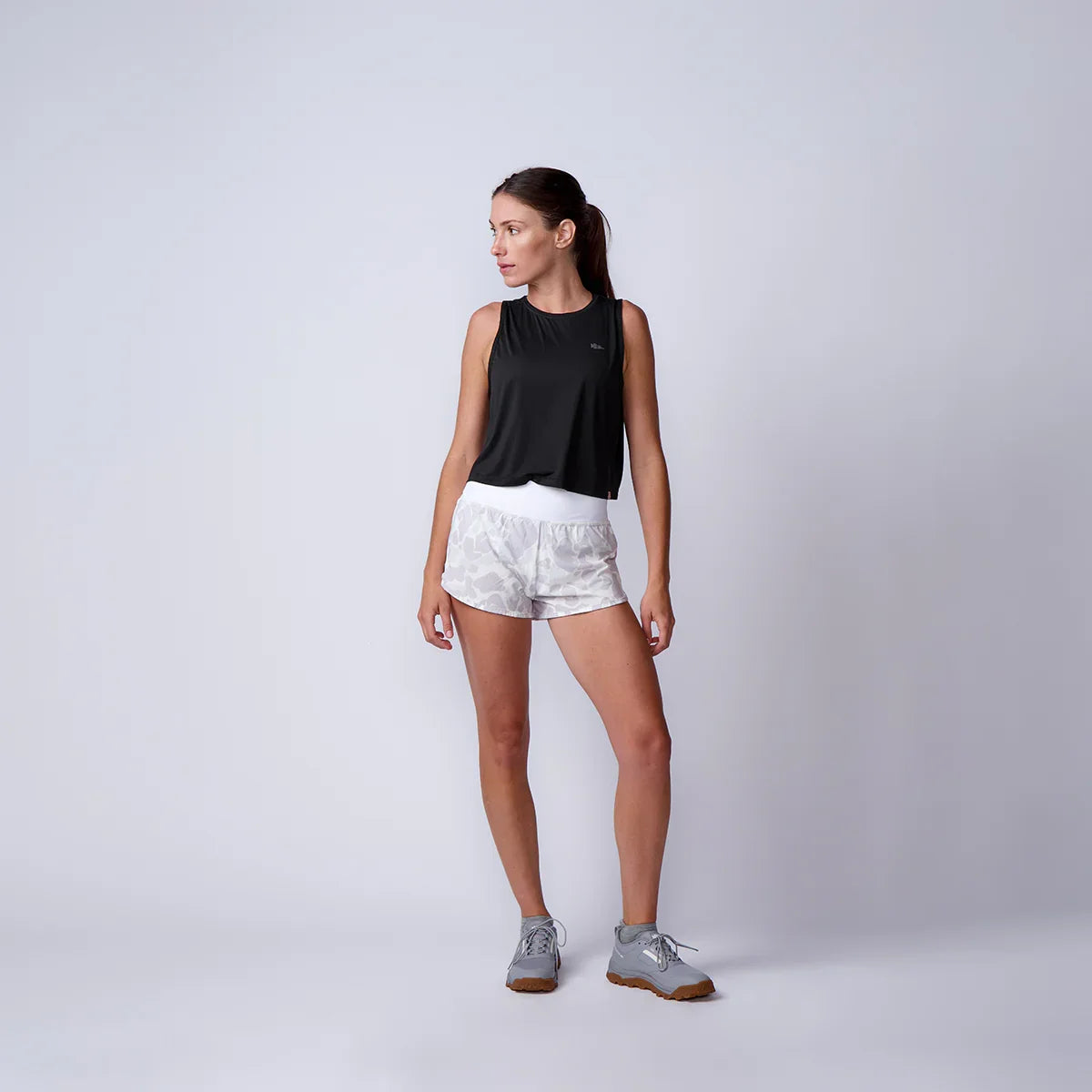 Woman wearing GORUCK rucking gear, black tank top, white camo shorts, and gray athletic shoes