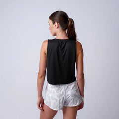 Woman wearing GORUCK black tank top and white camo shorts, shown from the back, studio setting
