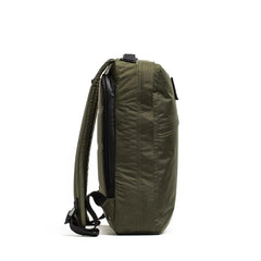 Side view of the GR0 - X-PAC, an olive green waterproof rucksack with black zippers and adjustable shoulder straps, made from X-PAC fabric, shown against a white background.