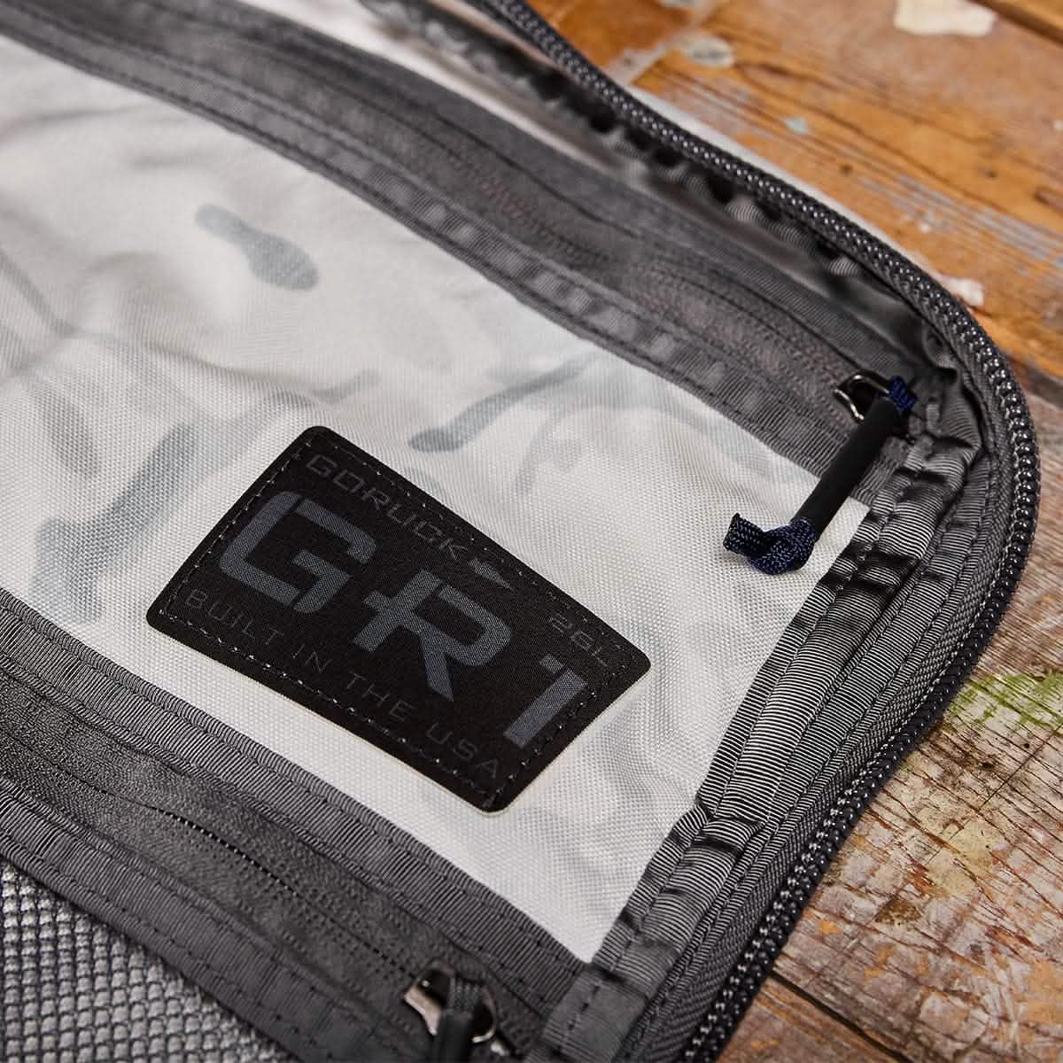 Close-up of the GR1 rucksack interior with a visible logo patch on wood, highlighting this American-made, Special Forces-grade backpack designed for everyday carry.