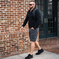 Man wearing GORUCK rucking gear and backpack walking by a brick wall outdoors