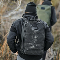 Man wearing a black GORUCK rucksack outdoors, hiking in rugged gear