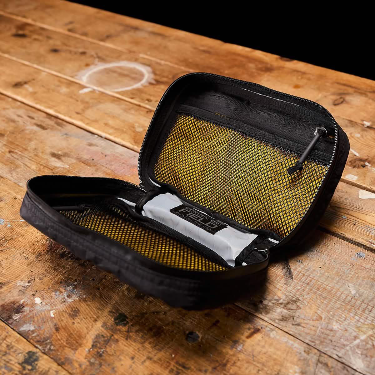 GORUCK zippered pouch with yellow mesh interior on wooden table, rugged rucking gear
