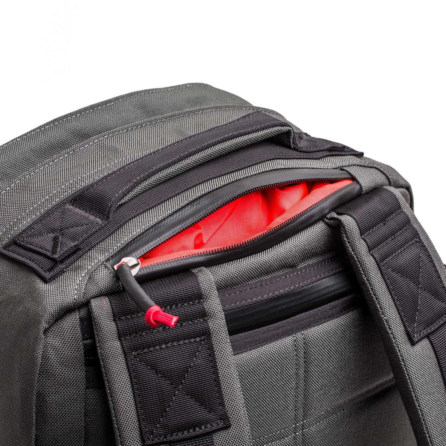 GORUCK 26L Armor Grey rucksack, close-up of durable black straps and open top zipper showing red liner.