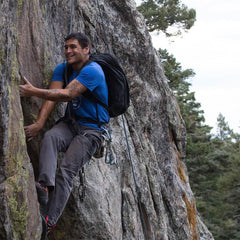 Man rock climbing outdoors with GORUCK backpack and gear, rugged mountain setting