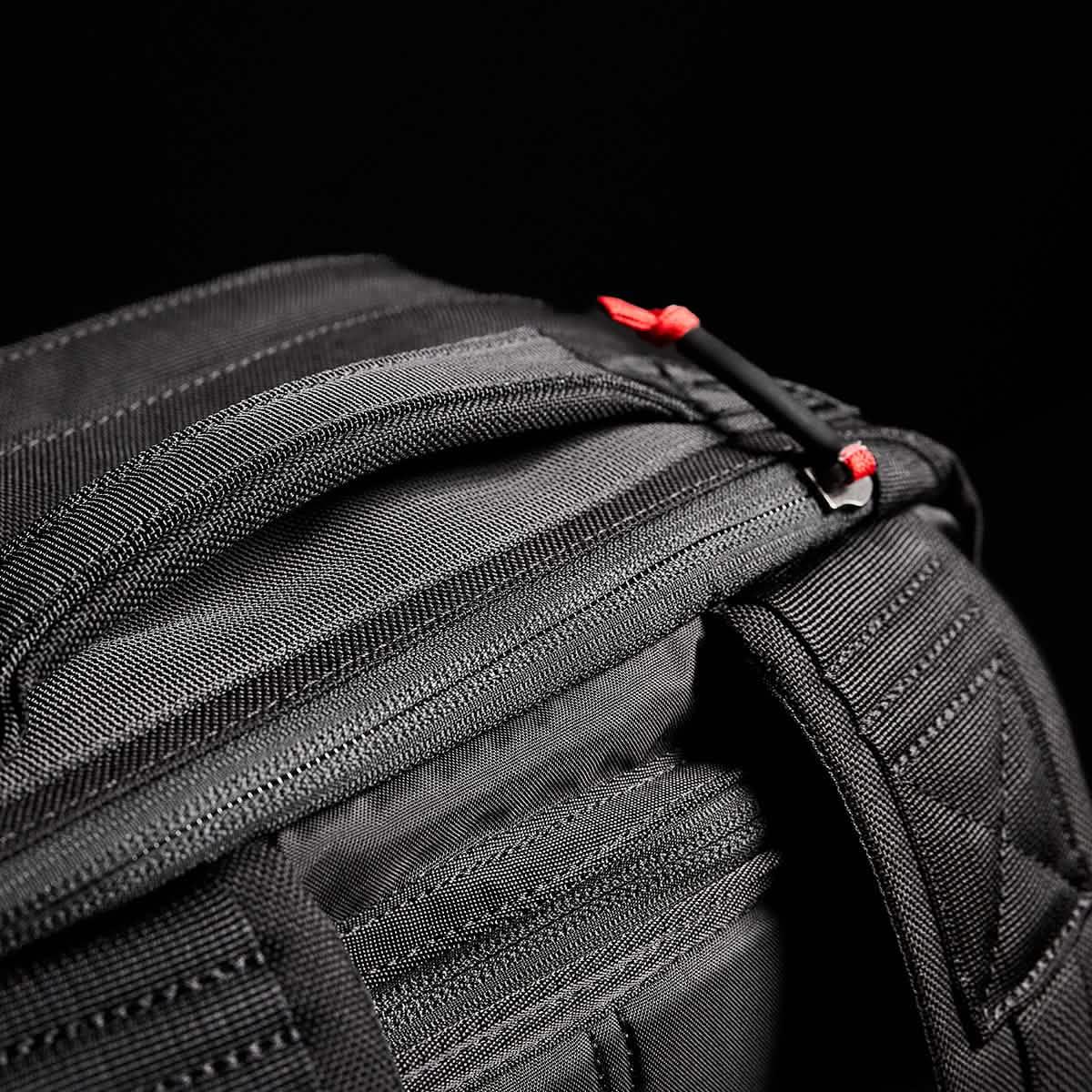 GORUCK black rucksack close-up showing durable fabric, sturdy zipper, and red zipper pulls