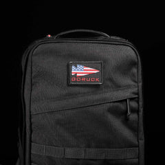GORUCK black rucksack with American flag patch and zipper, durable rucking gear on black background
