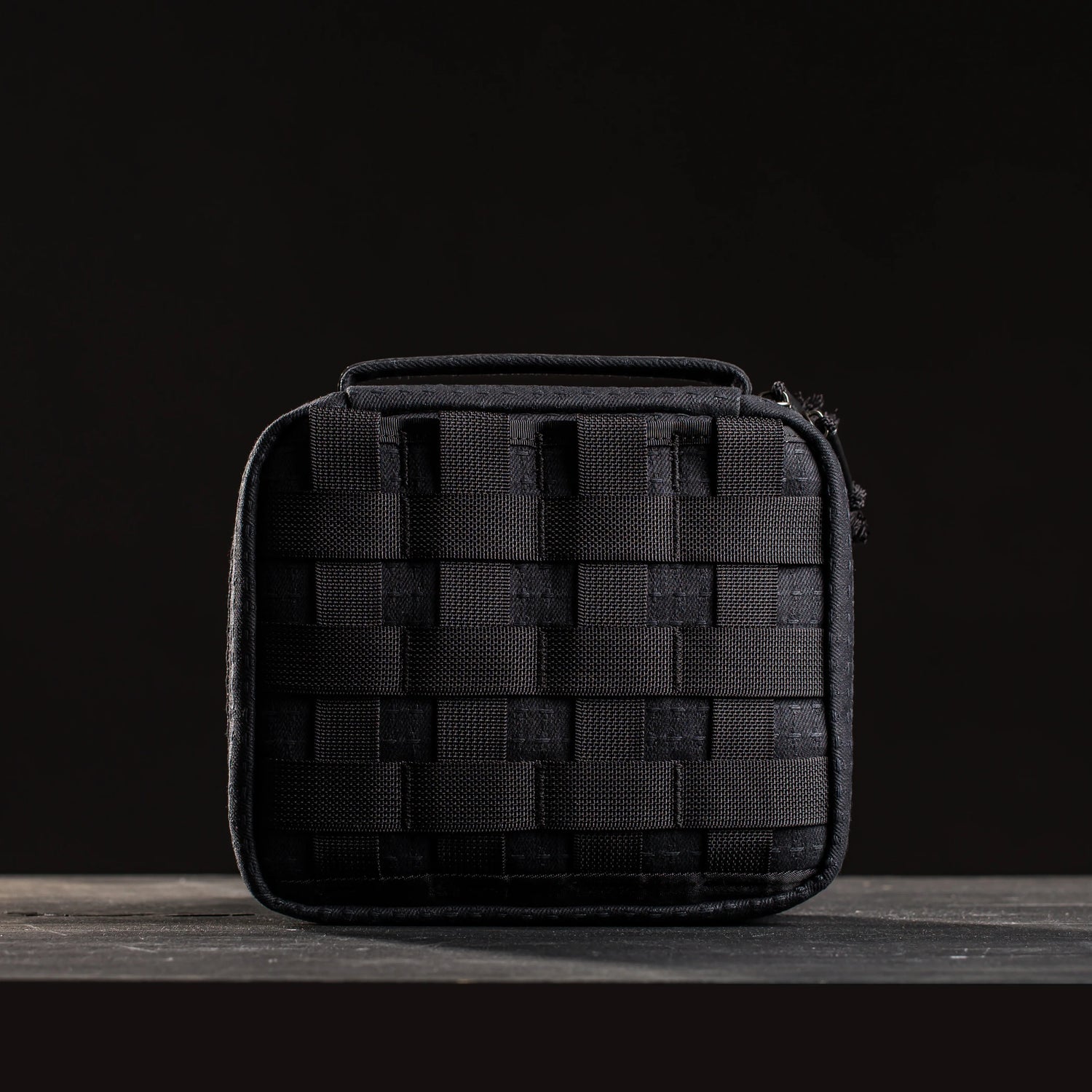 GORUCK black tactical field pouch with MOLLE webbing on a dark wood surface