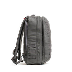 Side view of the gray GR2 - Cordura ruck travel backpack featuring multiple compartments and MOLLE webbing, displayed on a white background.