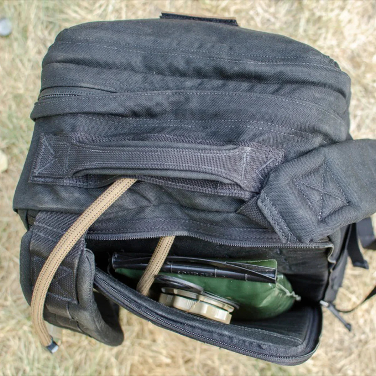 GORUCK black rucksack open on grass, showing rugged handle and organized gear inside