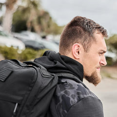 Man wearing GORUCK black grid fleece jacket with a rucksack outdoors