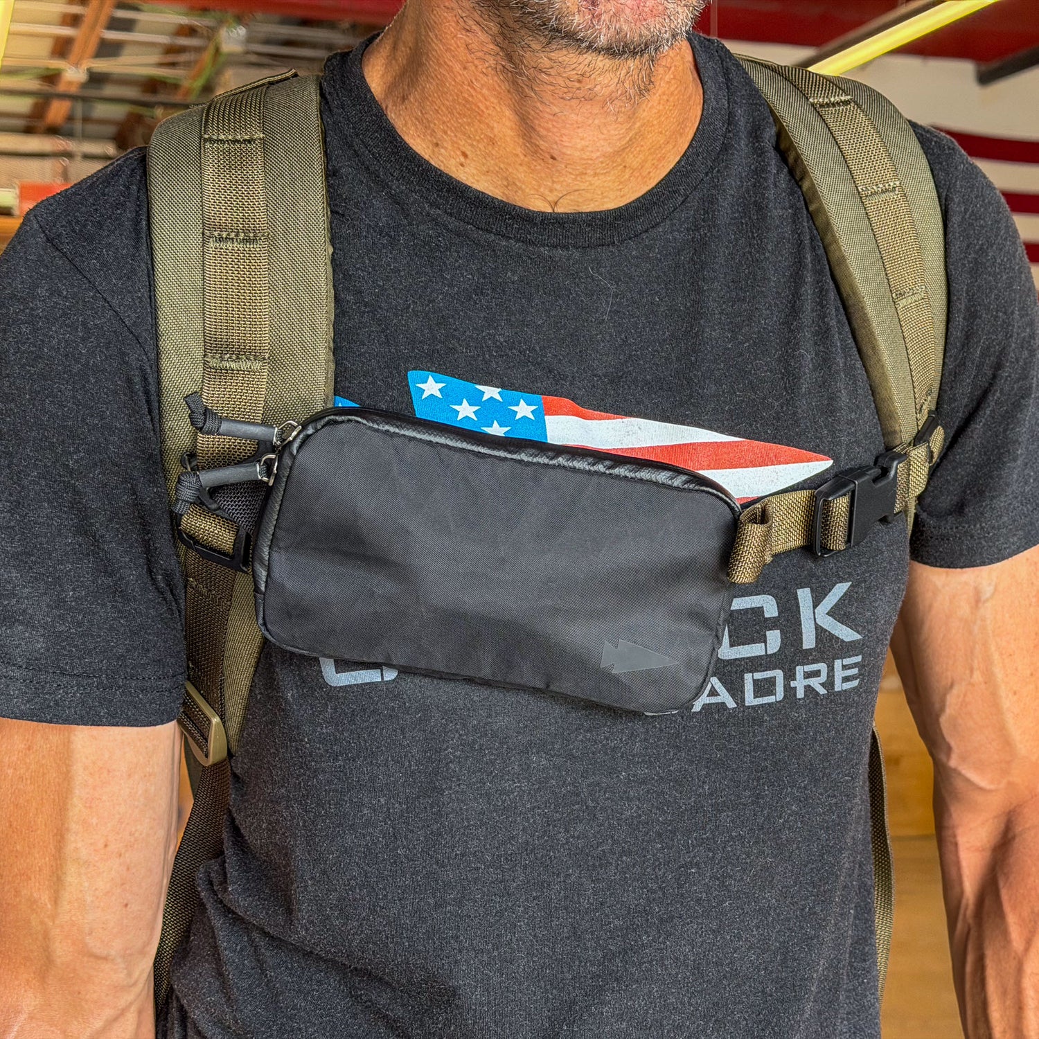 Man wearing a black t-shirt and backpack with the Sternum / Belt Pouch - Waterproof X-PAC attached to his chest strap for easy-access storage.