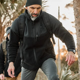Man rucking outdoors in GORUCK gear with backpack and black jacket on a trail.
