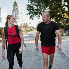 Two people rucking outdoors in GORUCK gear on a sunny suburban street