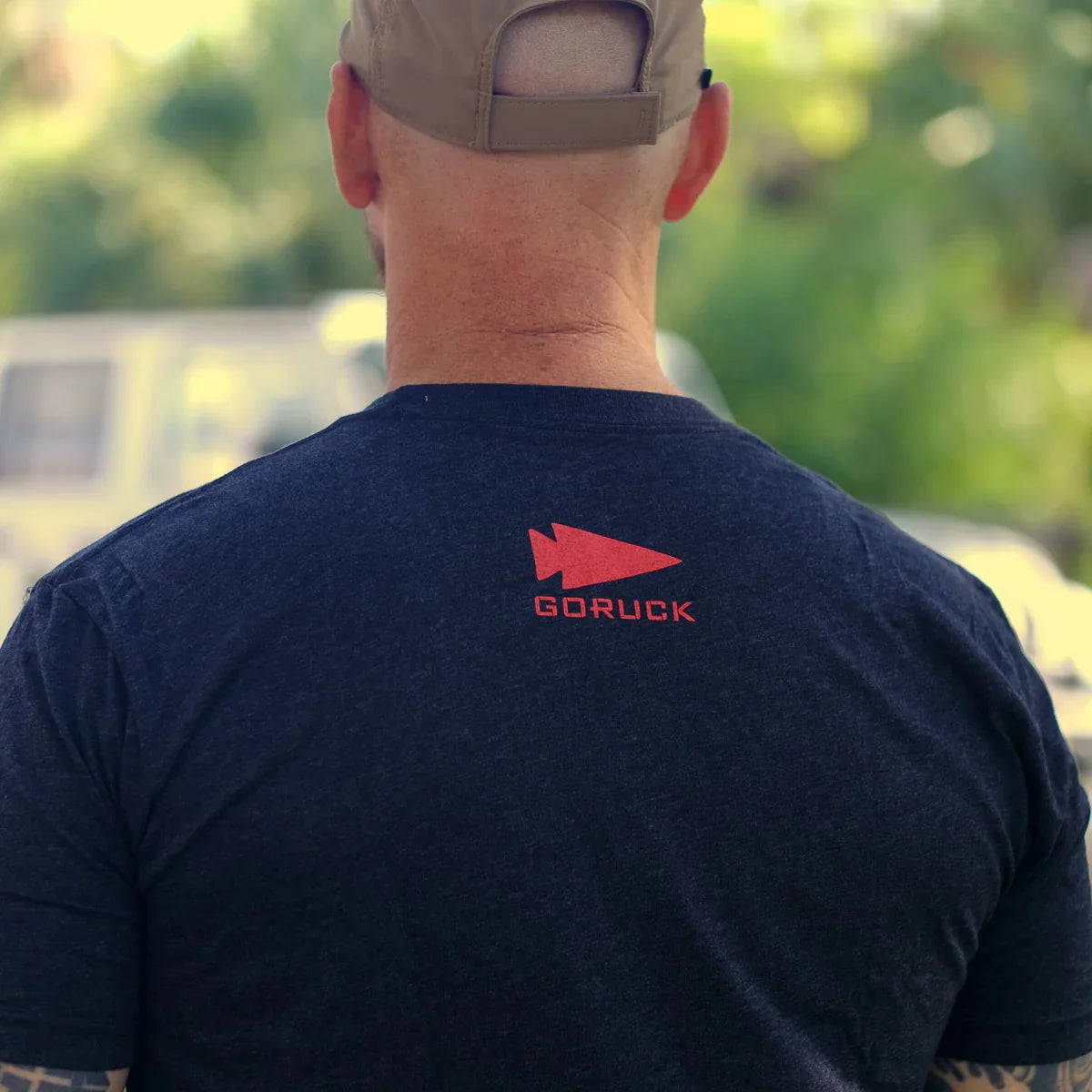 Man wearing black GORUCK t-shirt with red arrowhead logo outdoors