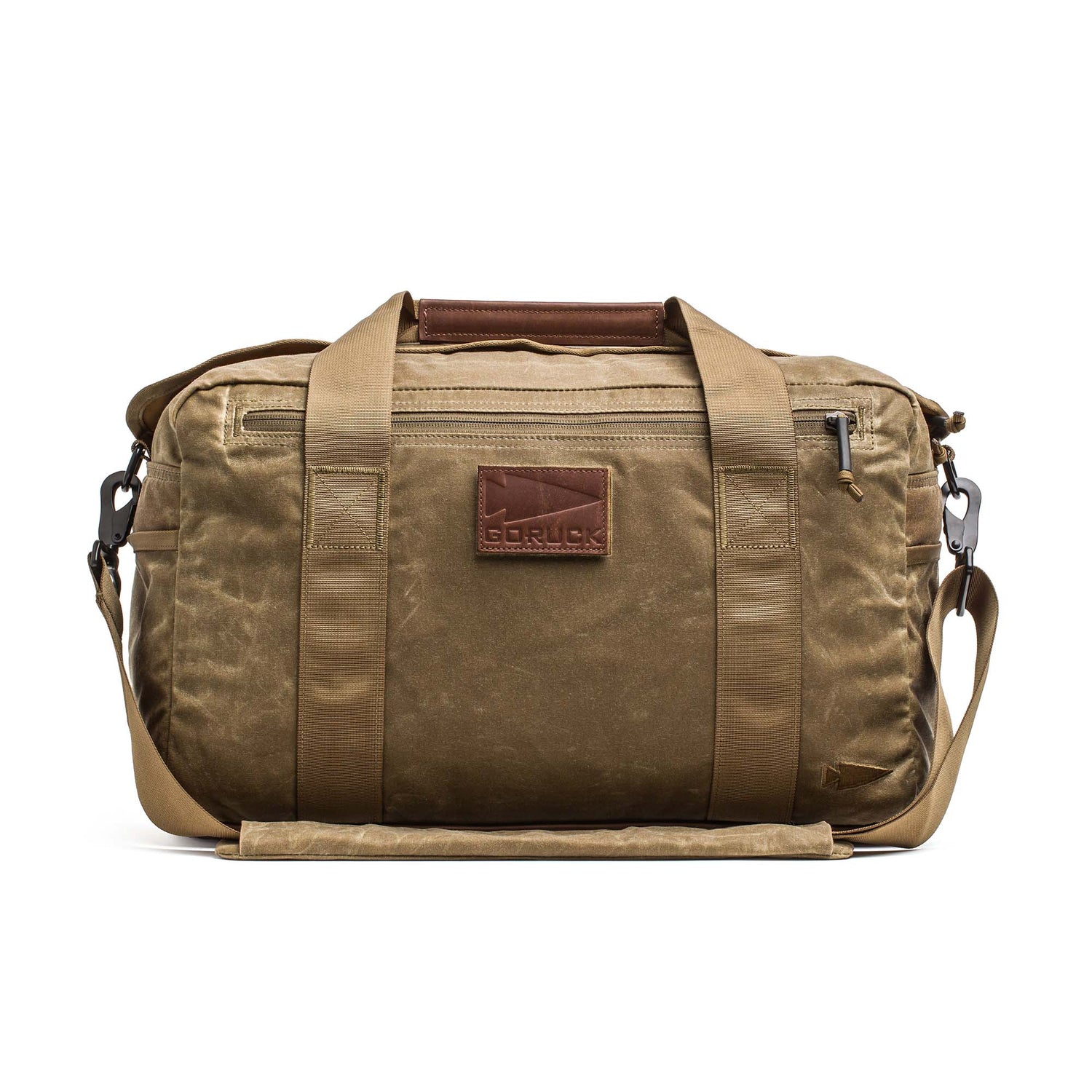 The Kit Bag - Waxed Canvas is a tan duffel inspired by classic aviator kit bags, featuring handles, a shoulder strap, and a leather front patch that reads 