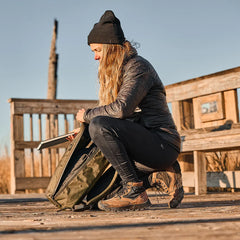 Woman outdoors in GORUCK MACV-2 Mid Top Chestnut Black boots, packing an olive rucksack