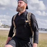 Man outdoors wearing GORUCK men's USA long sleeve performance half zip with rucksack