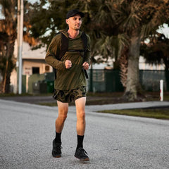 Man rucking outdoors wearing GORUCK Ranger Panties camo shorts, backpack, and black cap