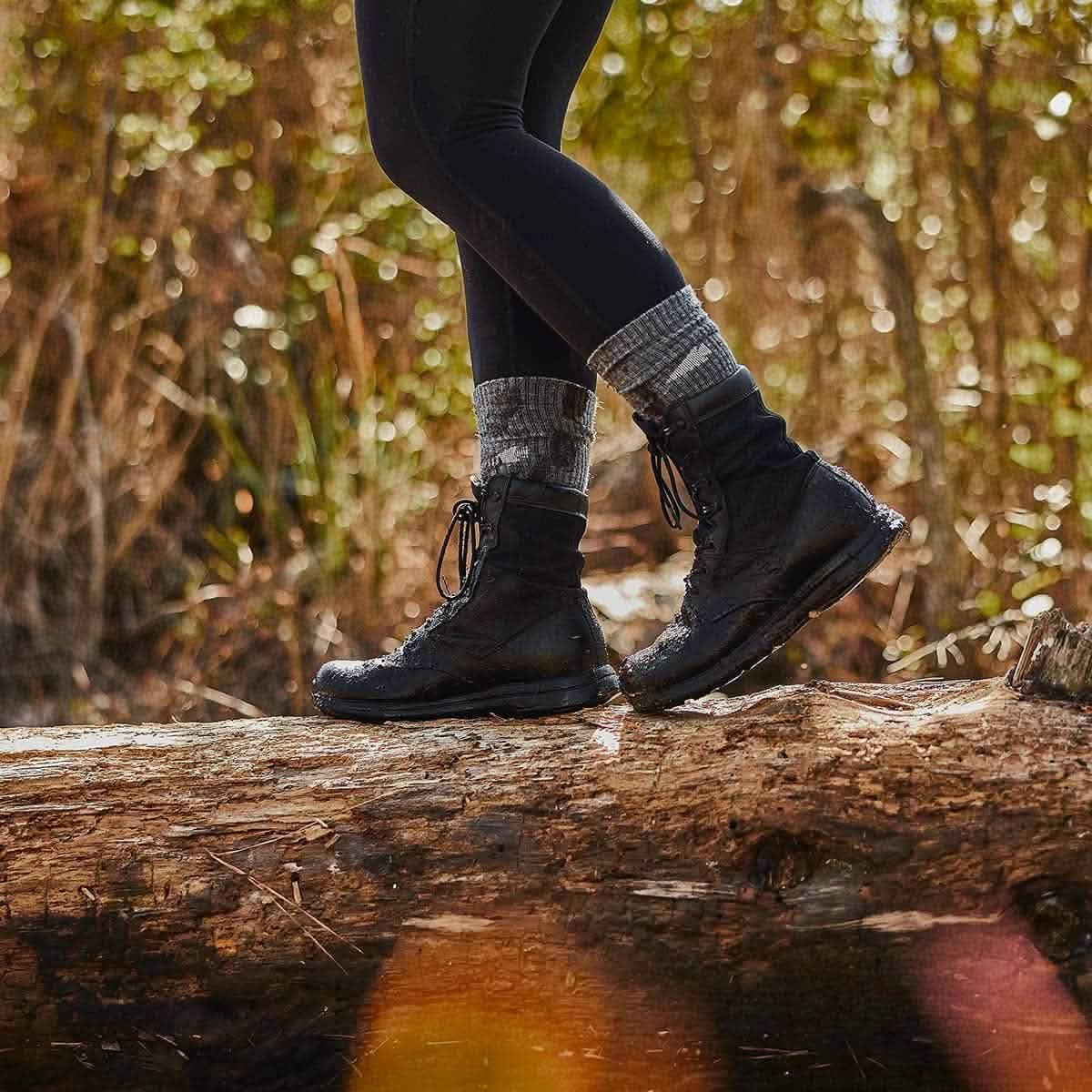 Person wearing charcoal merino wool socks and black boots walking on a log outdoors, GORUCK gear