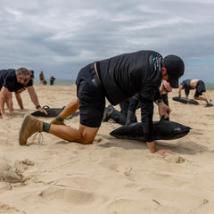 Men exercising on a sandy beach wearing GORUCK Ranger Green Merino Wool Socks and boots