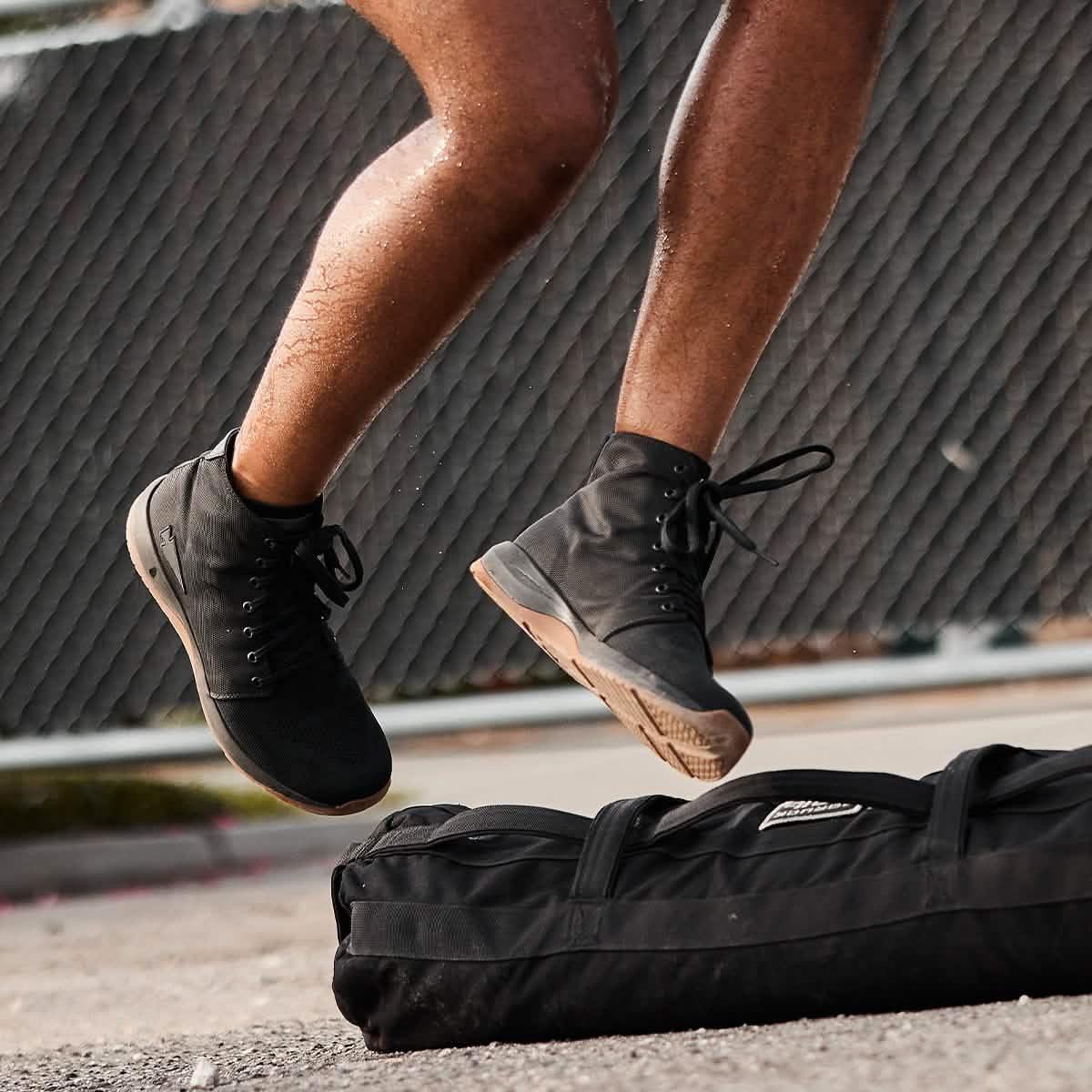 GORUCK rucking shoes in action during outdoor fitness training, jumping over a sandbag