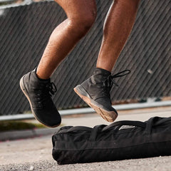 GORUCK rucking shoes in action during outdoor fitness training, jumping over a sandbag