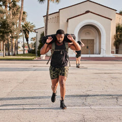 Man rucking with weighted backpack and sandbag outdoors, GORUCK fitness gear