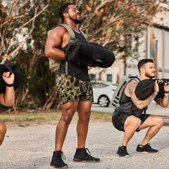 Men rucking with weighted sandbags and backpacks outdoors, wearing GORUCK gear