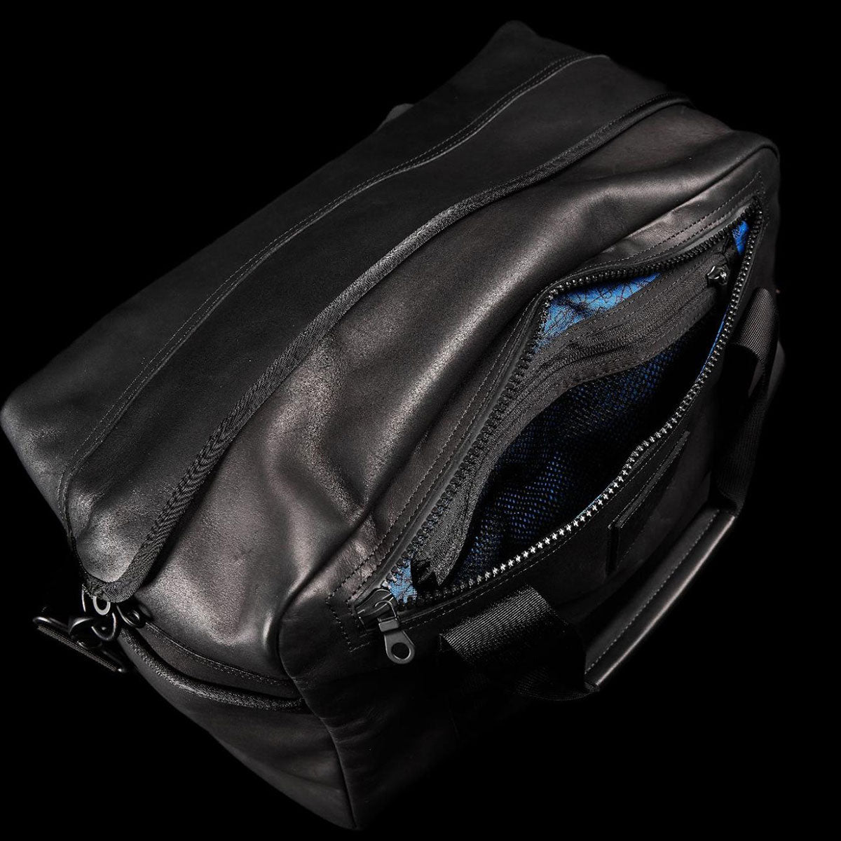 Black leather duffel bag with a partially open zipper showing blue interior lining and mesh pocket.