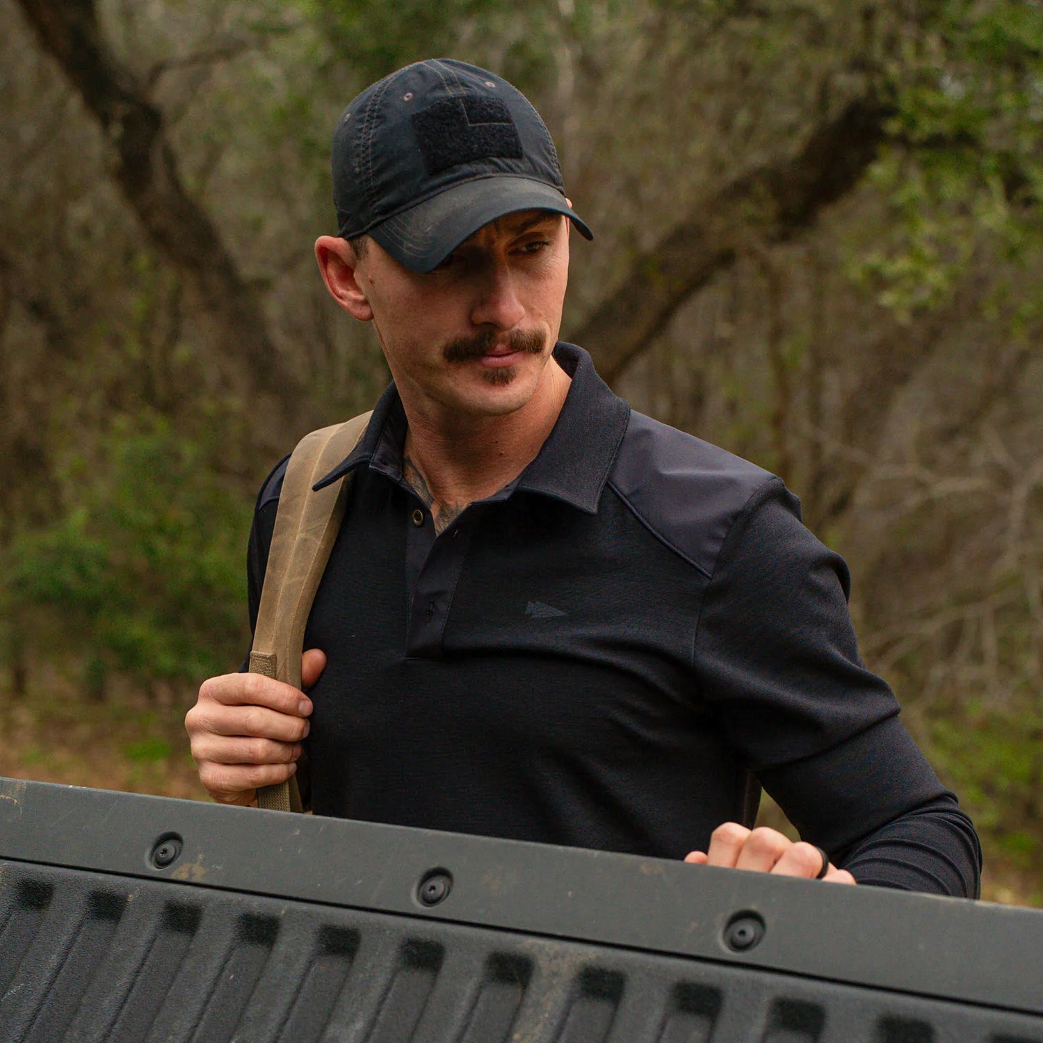 Man wearing black GORUCK cap and rucking shirt outdoors, carrying backpack strap