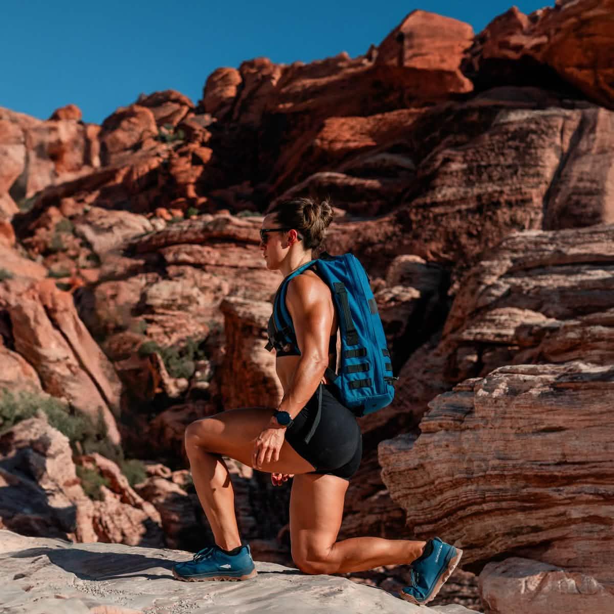 Athletic woman rucking with GORUCK backpack on rocky desert trail, outdoor fitness gear
