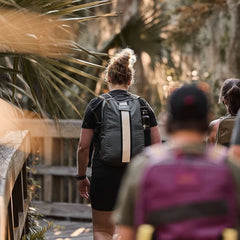 People rucking outdoors with GORUCK backpacks on a wooded trail boardwalk