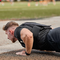 Man doing outdoor push-ups wearing GORUCK rucking gear on a running track